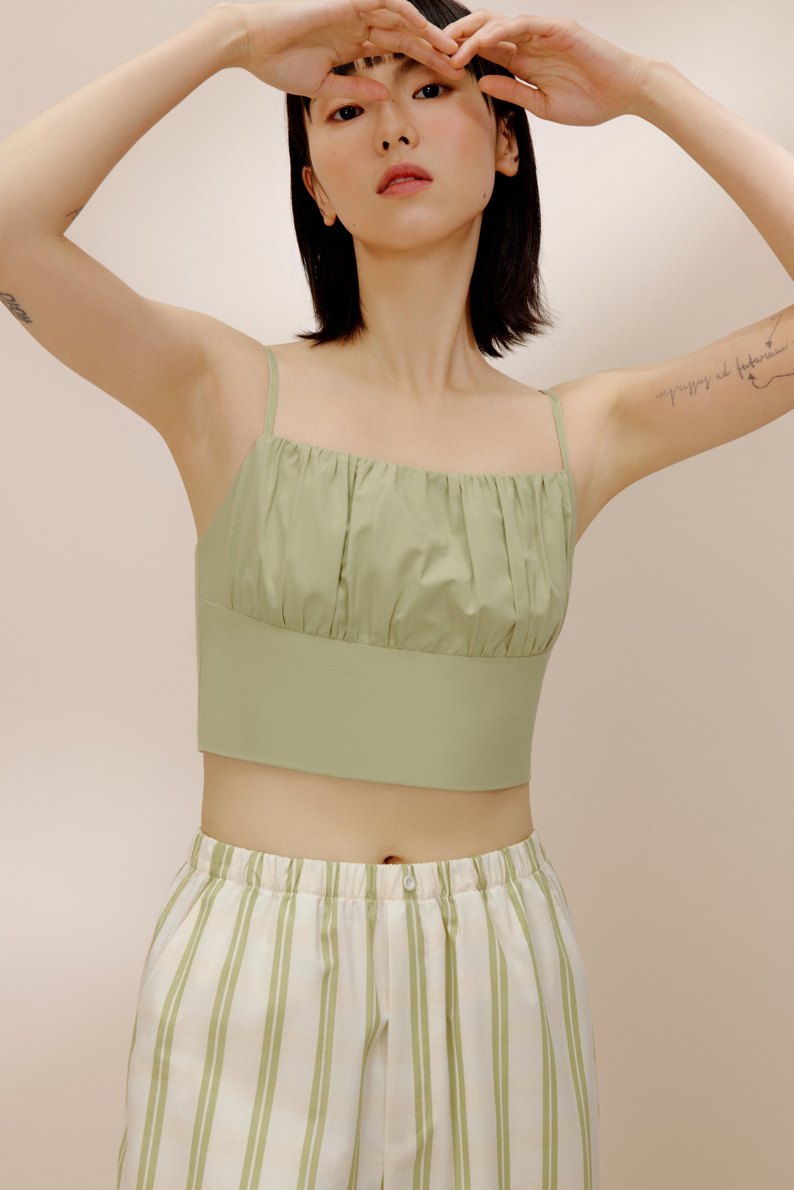 Woman wearing green tank top and white and green striped pajama pants