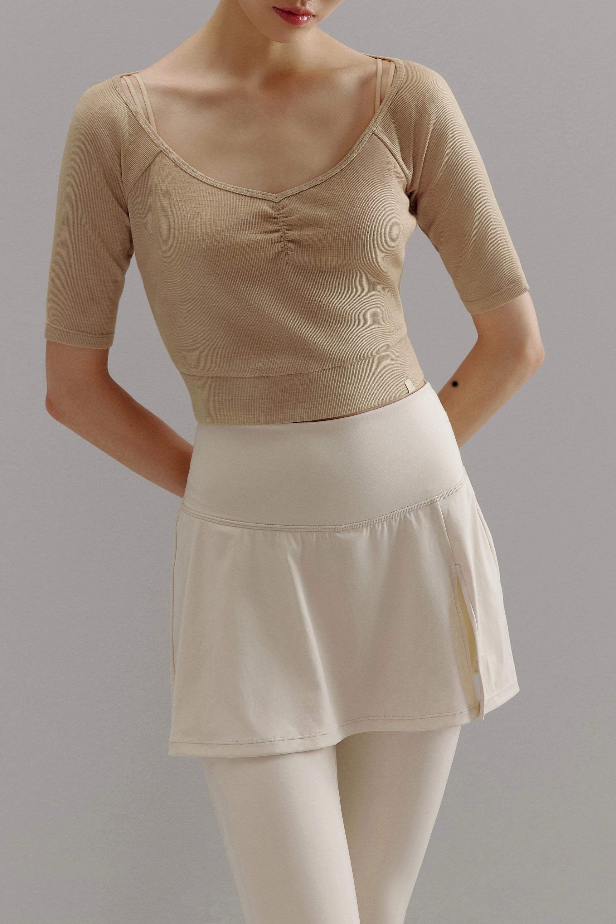 Woman wearing beige V-neck sweater.
