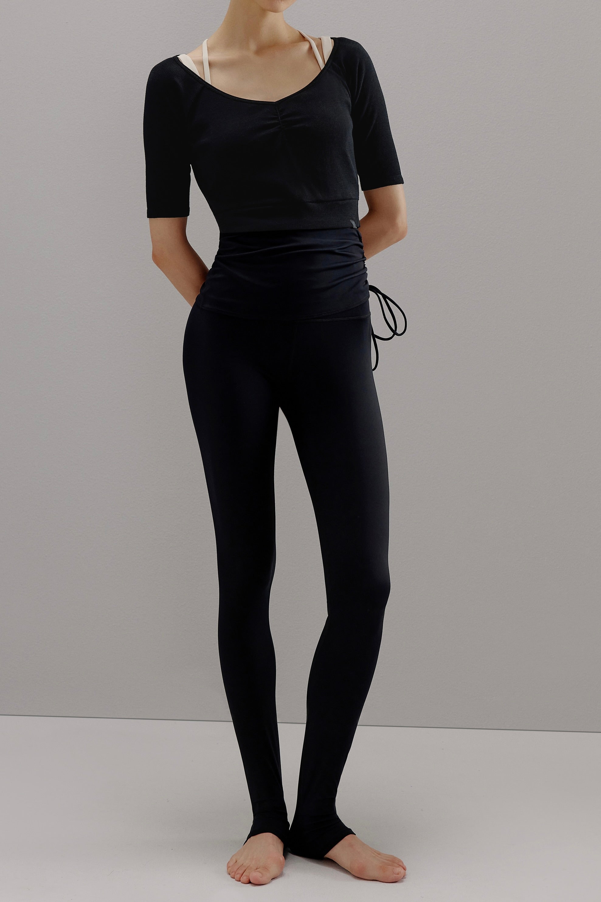 Woman wearing black V-neck sweater and black leggings. 