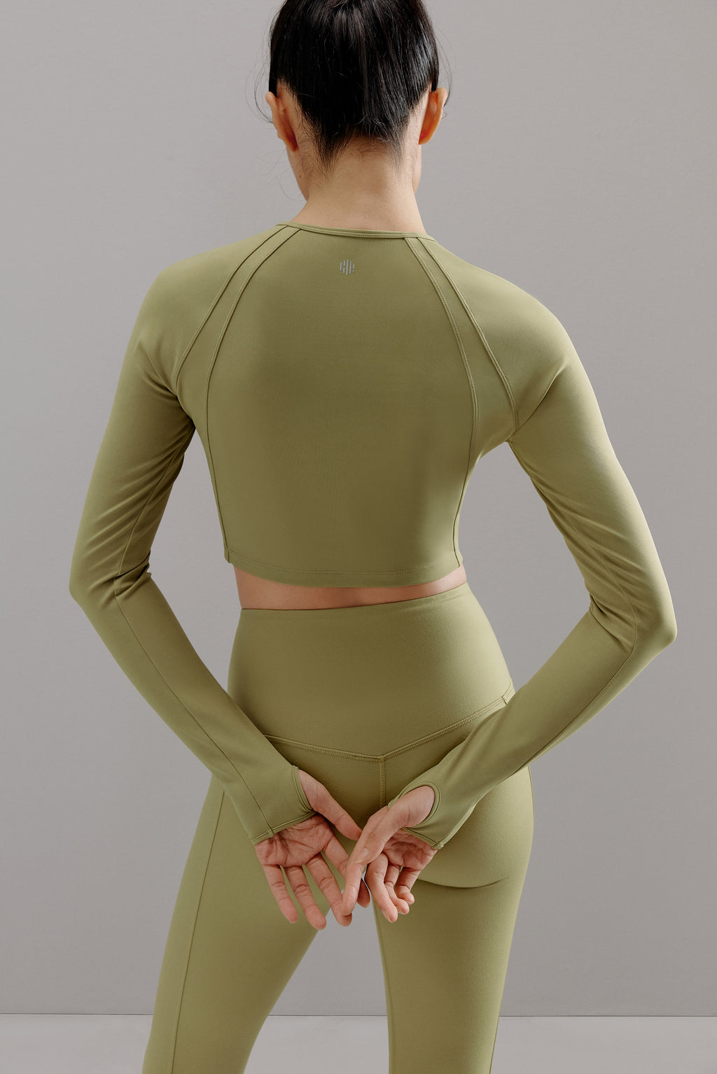 Back view of woman wearing green cropped top and matching leggings.