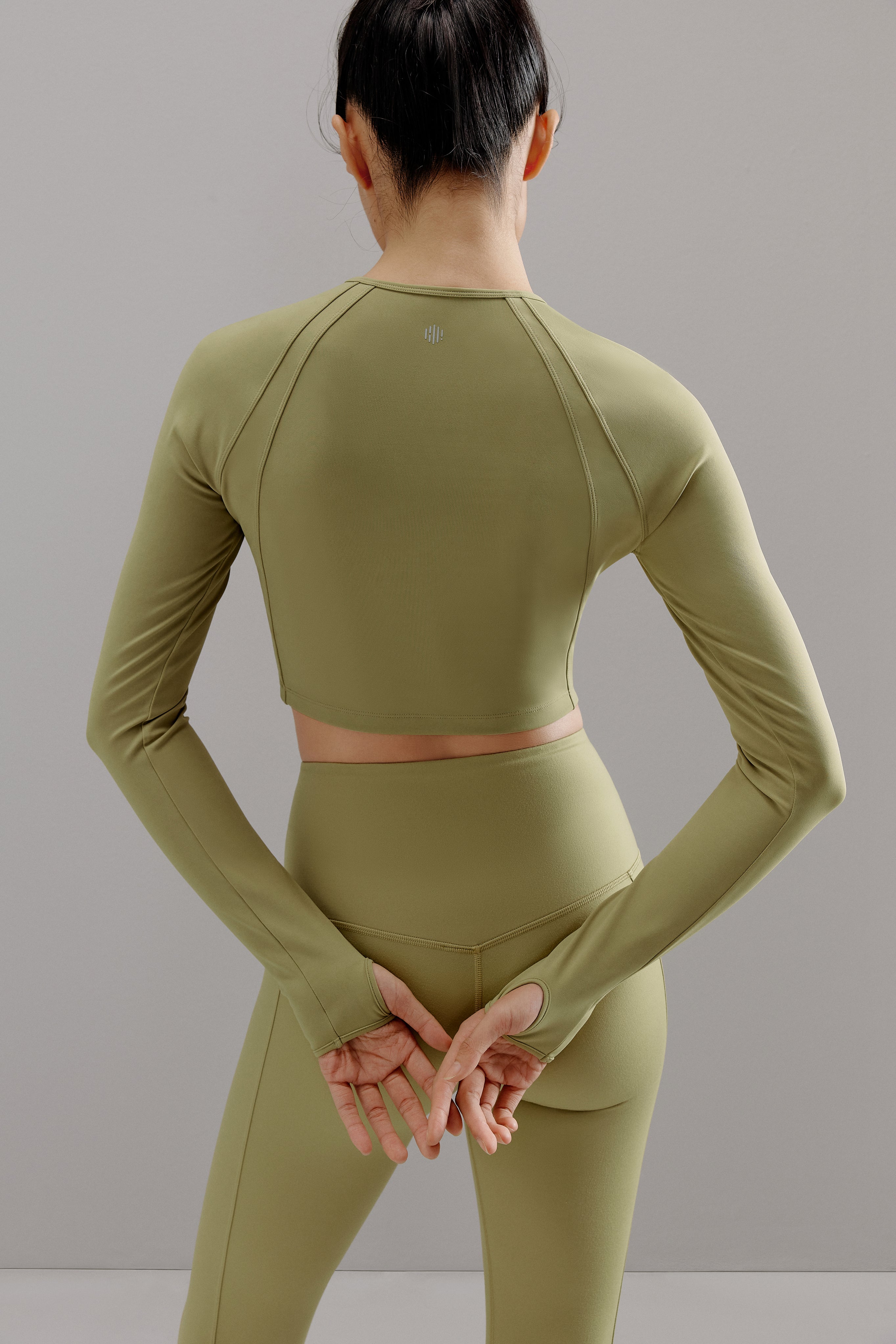 Back view of woman wearing green cropped top and matching leggings.