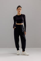 Woman wearing dark gray cropped top with black joggers.
