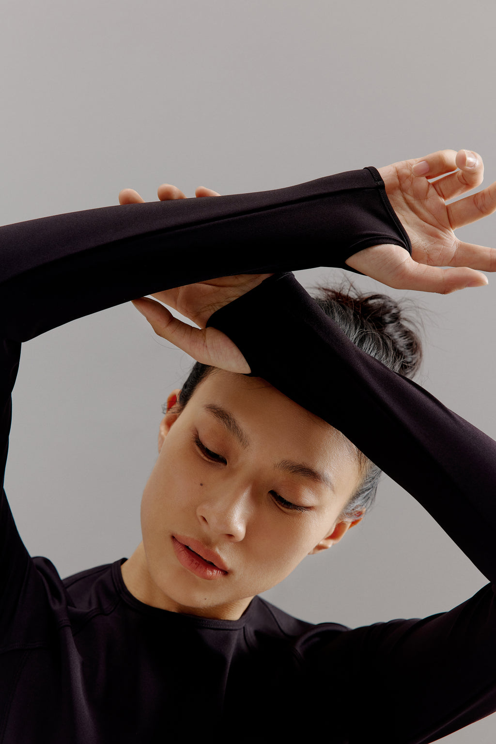 Woman crossing arms wearing dark gray cropped top.