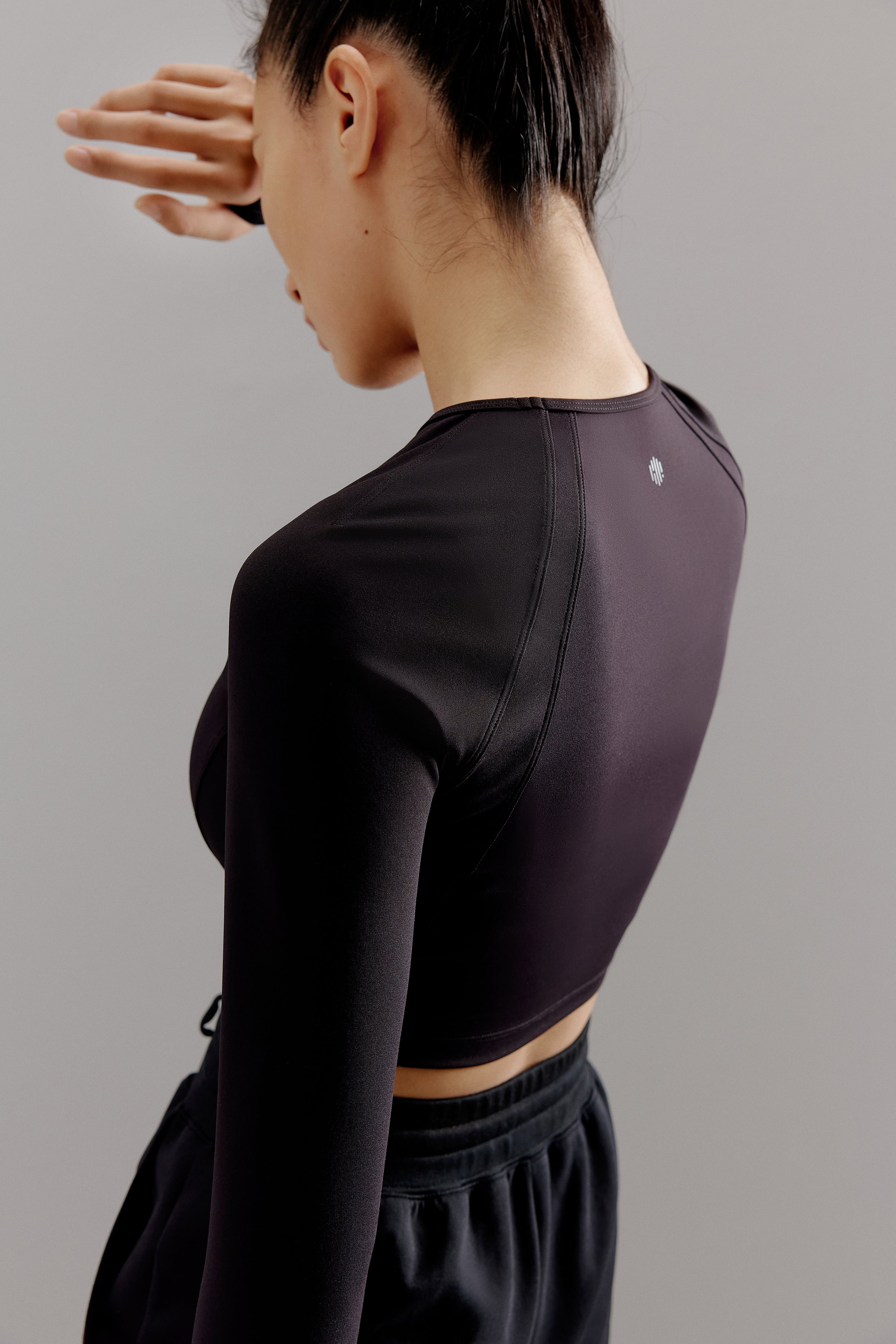 Back side view of woman wearing dark gray cropped top.