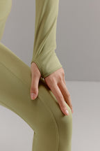 Close-up view of thumbhole design on green cropped top.