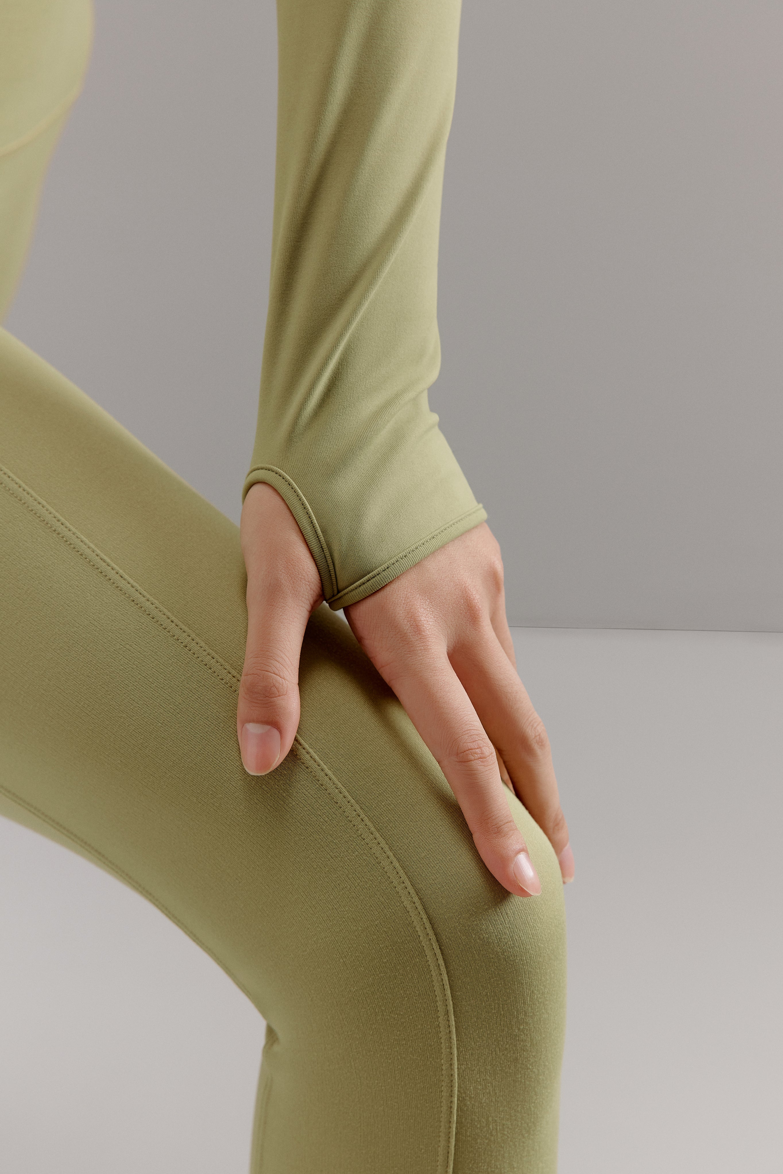 Close-up view of thumbhole design on green cropped top.