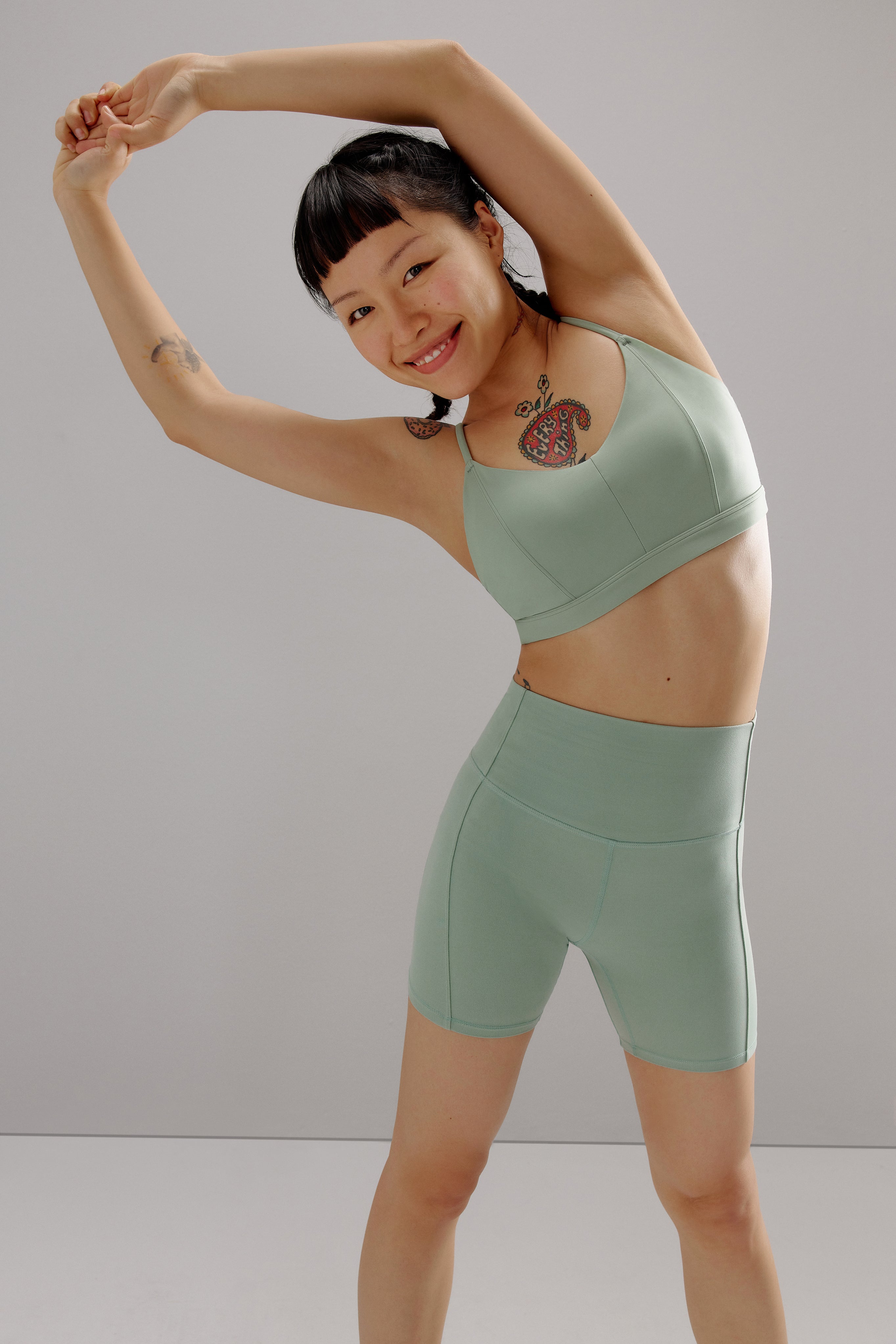 A woman wears a teal sports bra and shorts.