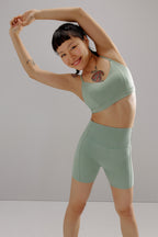 Woman in a side bend wearing aqua sports bra and matching biker shorts