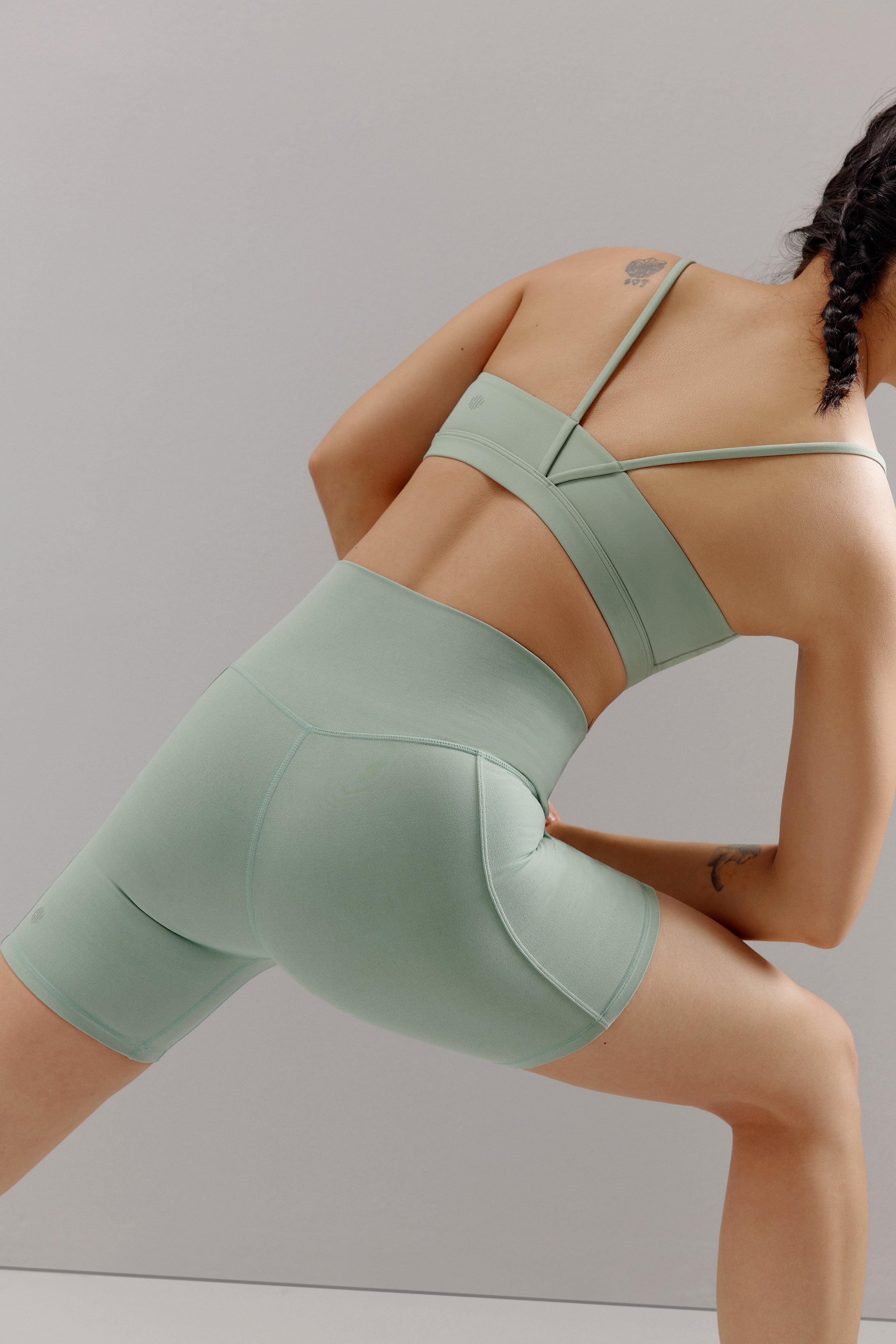 A woman wears a teal sports bra and shorts.