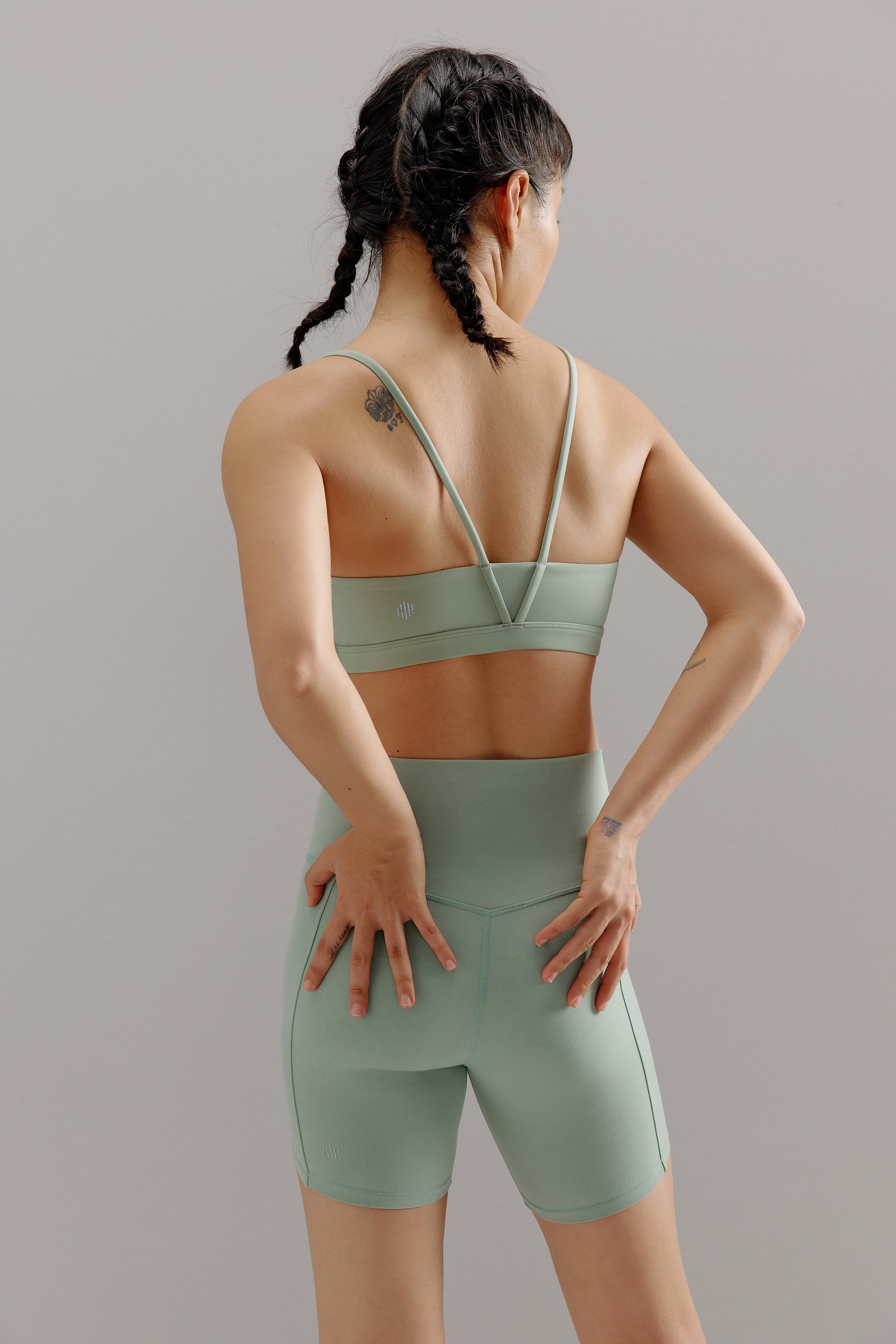 A woman wears a teal sports bra and shorts from back