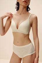 Woman wearing off-white lace bra and matching briefs