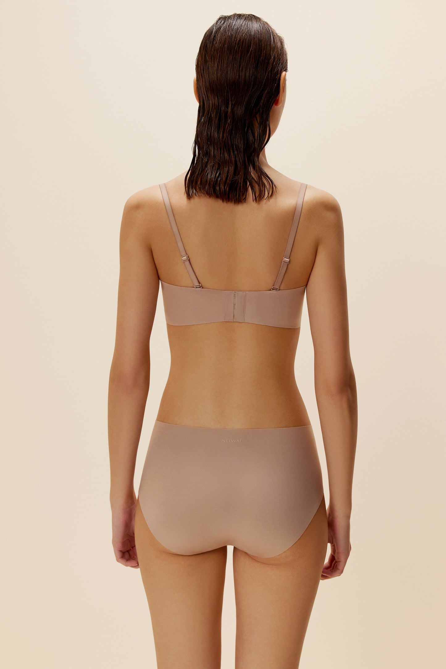 Back view of woman wearing blush-colored bra with straps and underwear set
