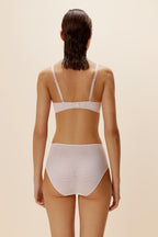 A woman wears a white bra and brief from back.