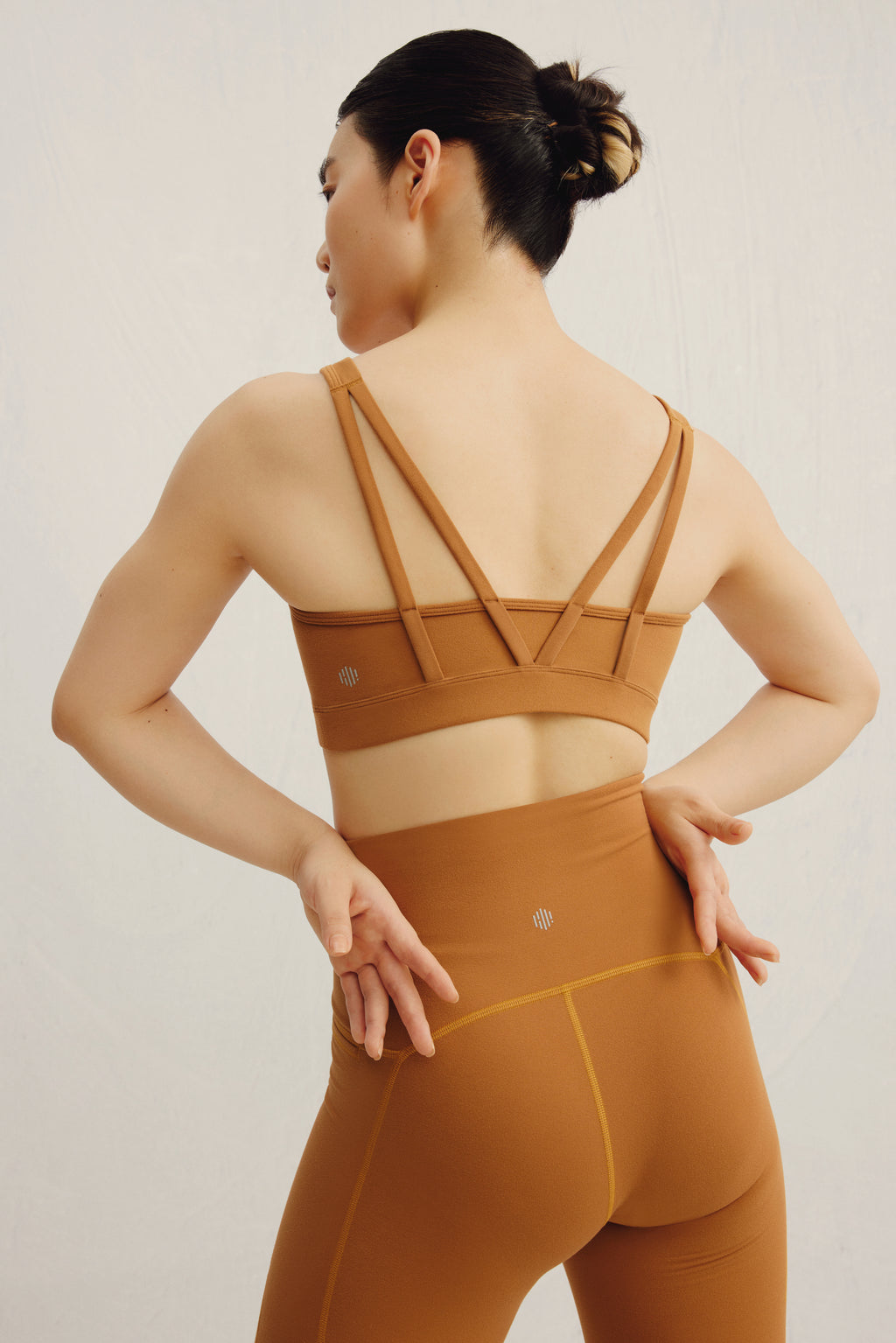 woman facing back, wearing a yellow M back sports bra and leggings