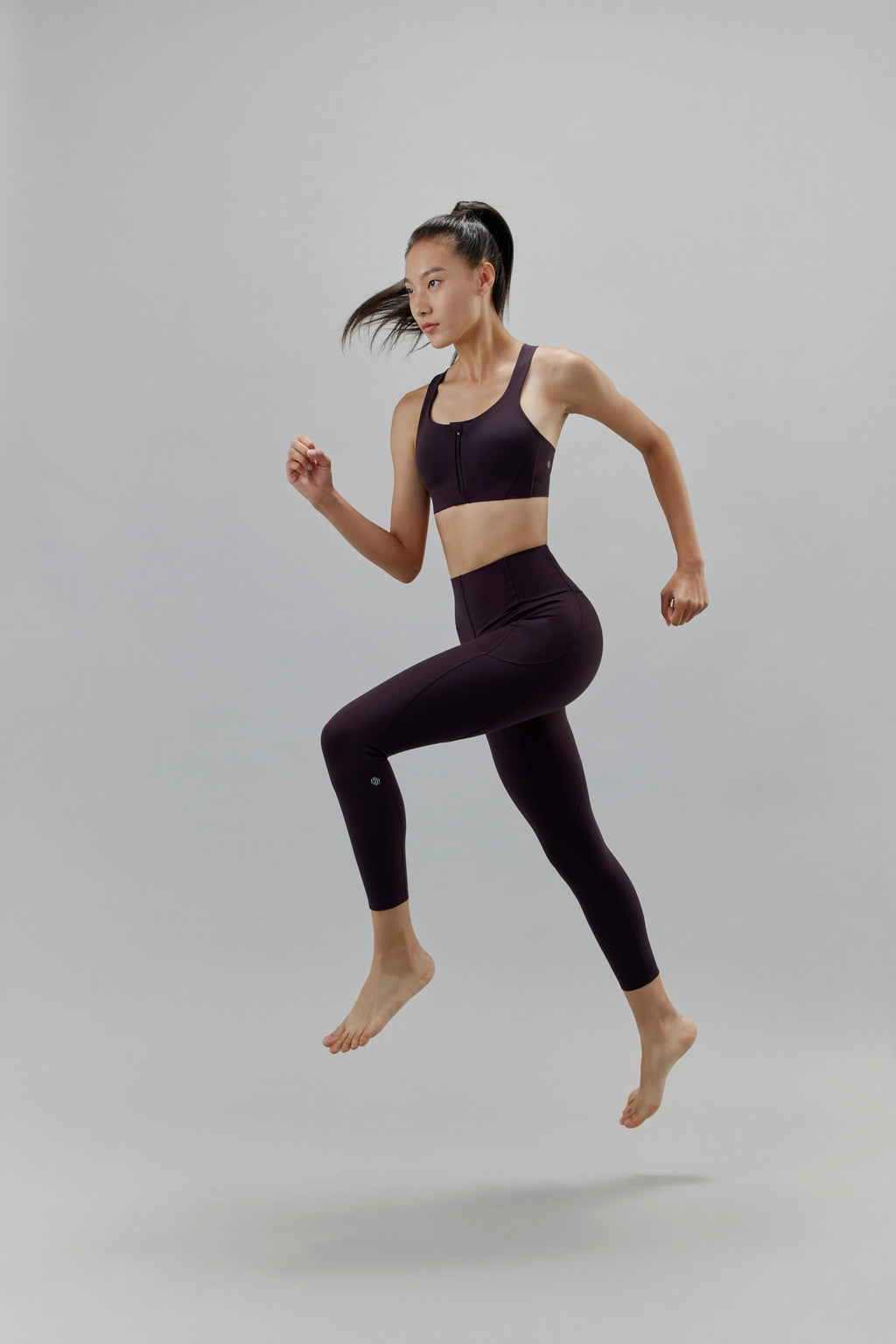 Woman jumping wearing black leggings and matching sports bra