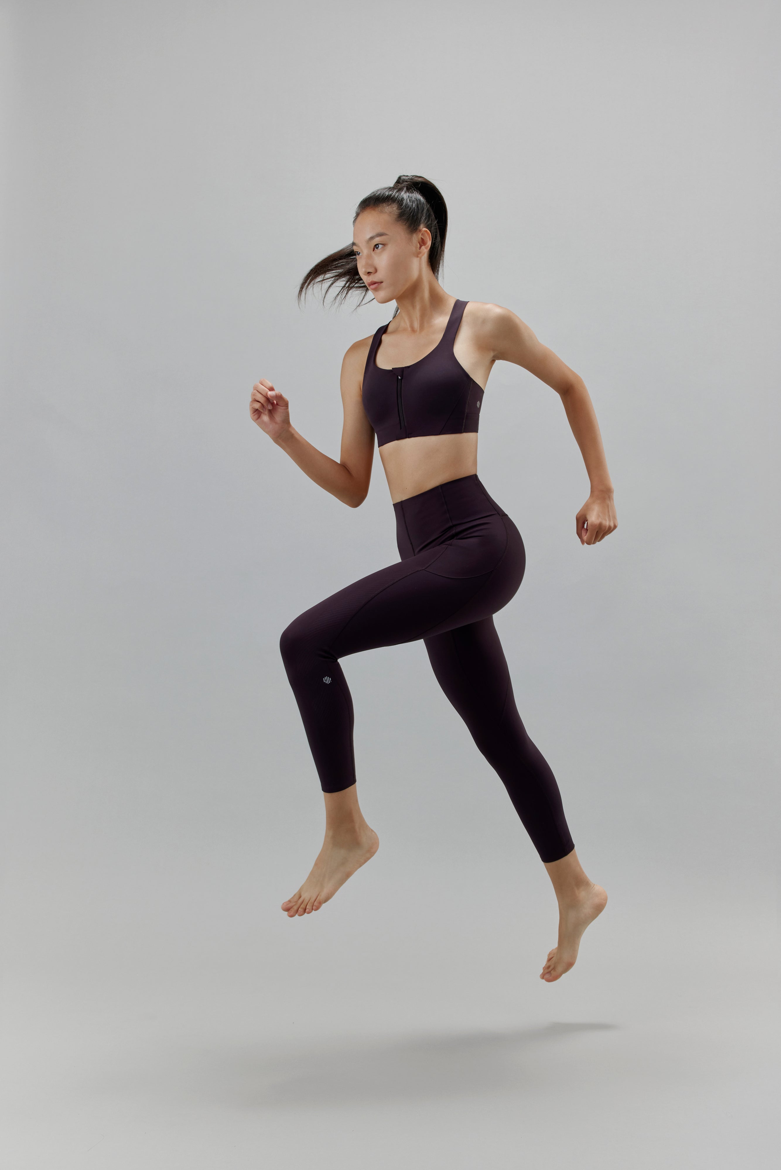 Woman jumping wearing black leggings and matching sports bra