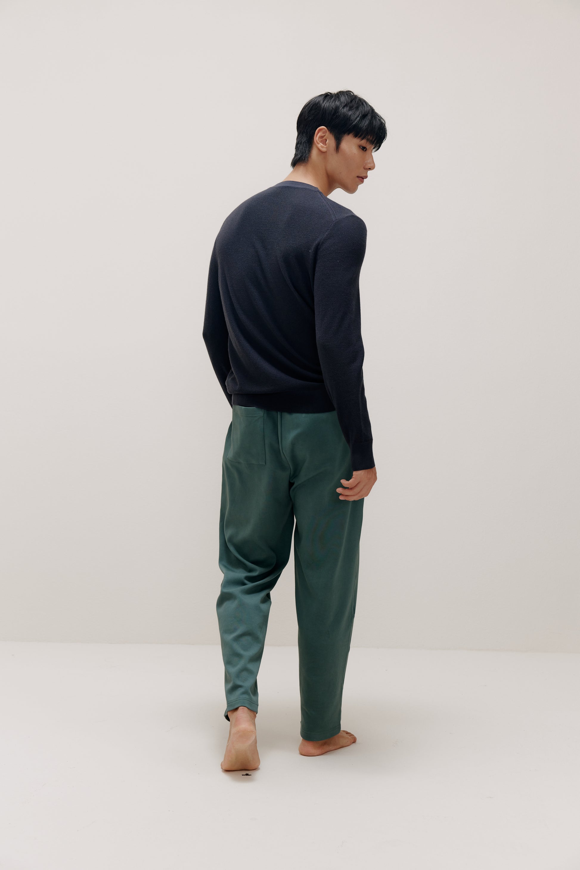 back of man in navy sweater and green pants
