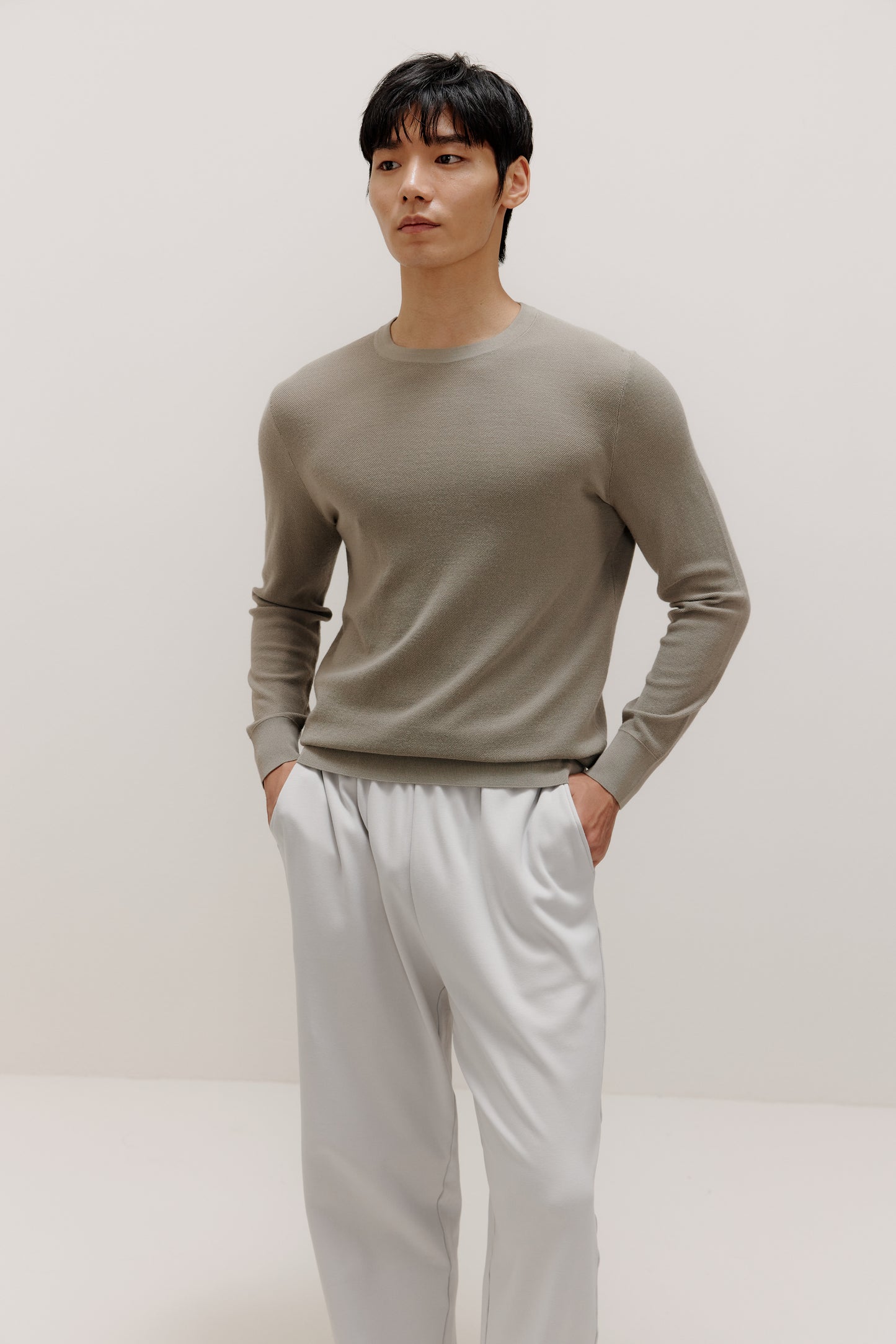 man in khaki sweater and grey pants