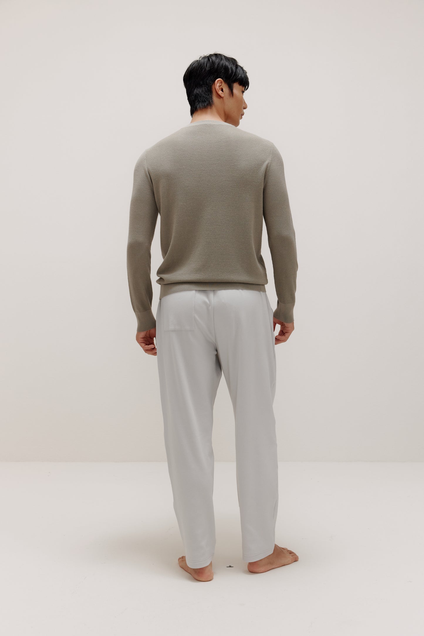 back of man in khaki sweater and grey pants