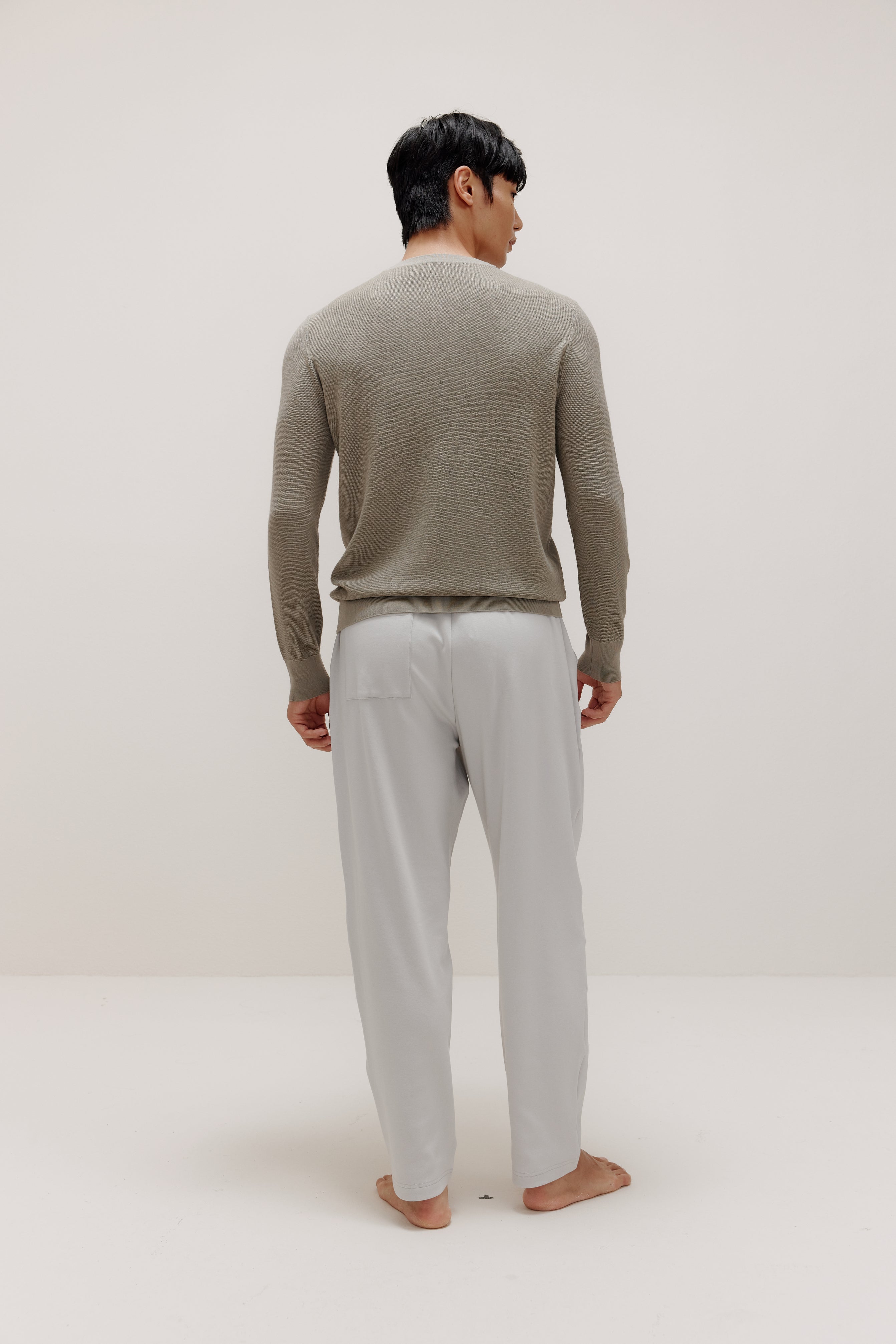 back of man in khaki sweater and grey pants