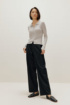A woman wears a gray silky wool zip-up cardigan, black pants, and black shoes.