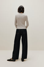A woman wears a gray silky wool zip-up cardigan and black pants from back
