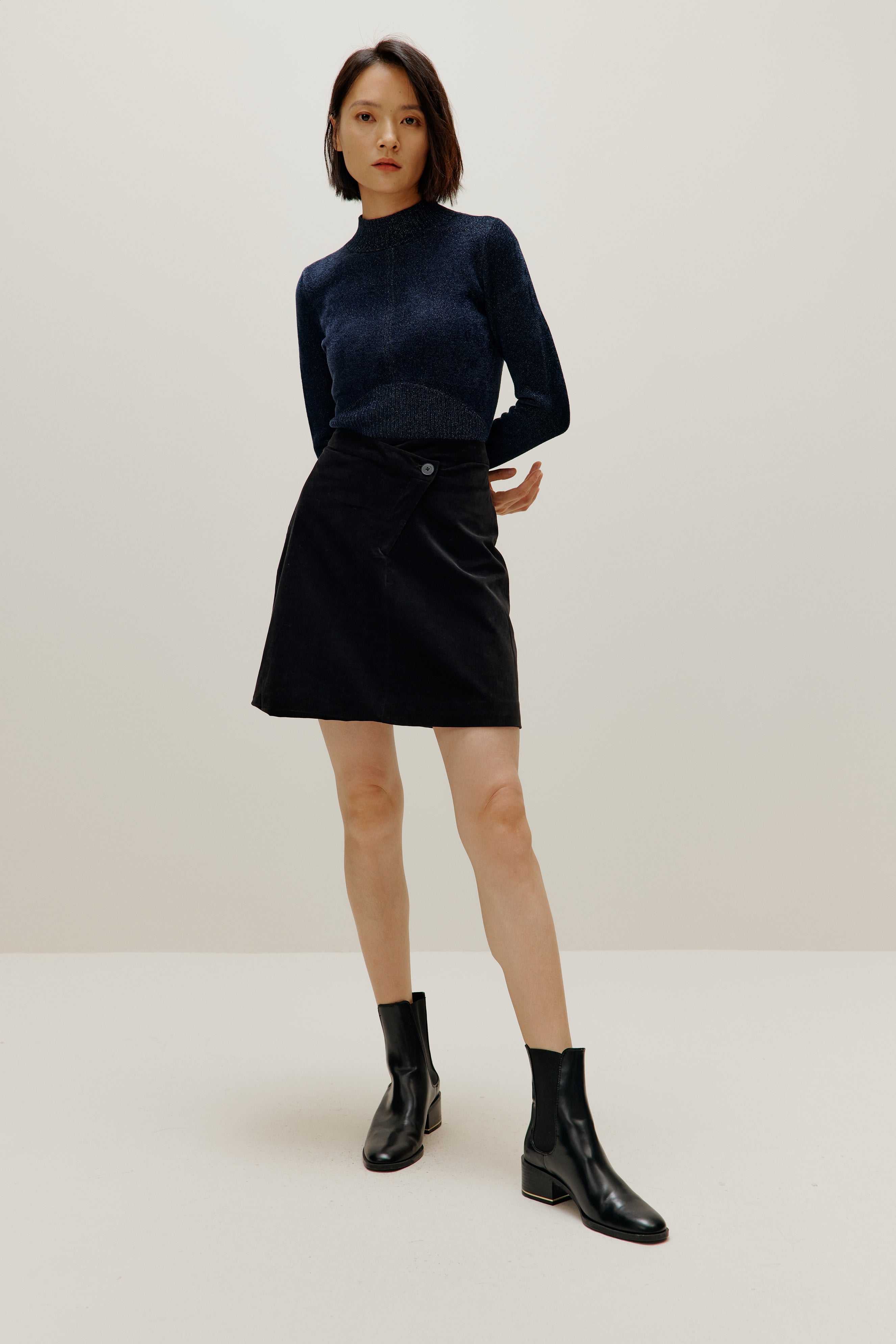 woman wearing blue shimmer mock neck sweater and a black skirt