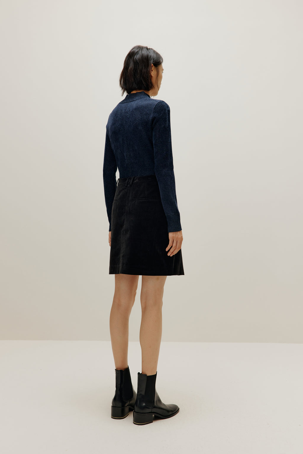 woman wearing blue shimmer mock neck sweater and a black skirt
