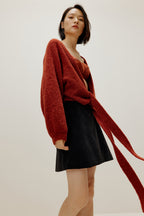 woman wearing a red wrap Cardigan and black skirt
