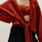 woman wearing a red wrap cardigan and red bra paired with black skirt