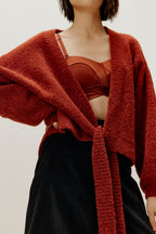 woman wearing a red wrap cardigan and red bra paired with black skirt