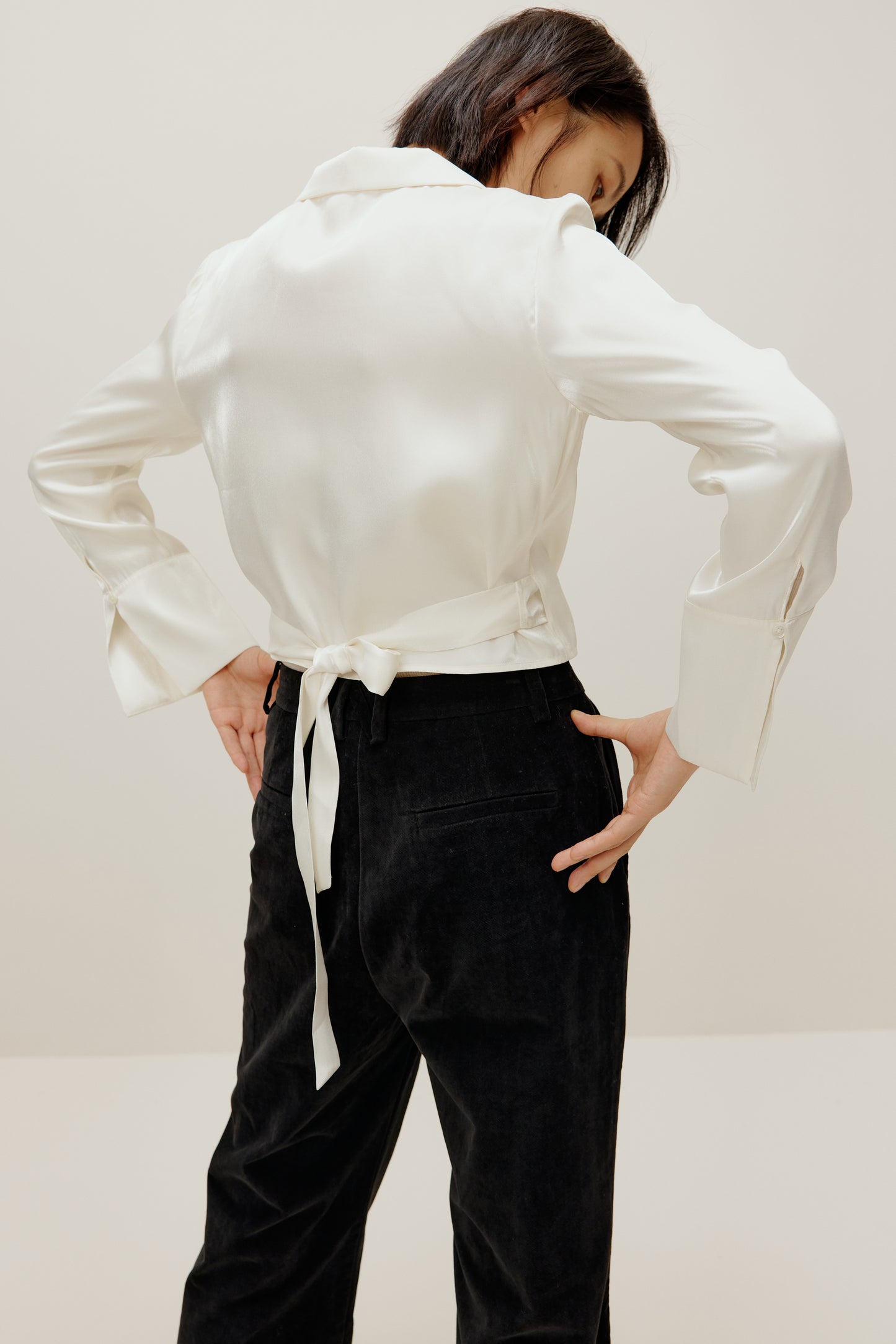 back of woman in white satin shirt and black bottoms