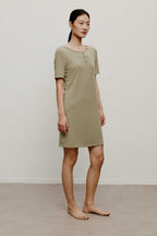 Woman in a green pajama dress, facing right.