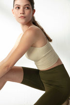 woman in cream sports bra and green biker shorts
