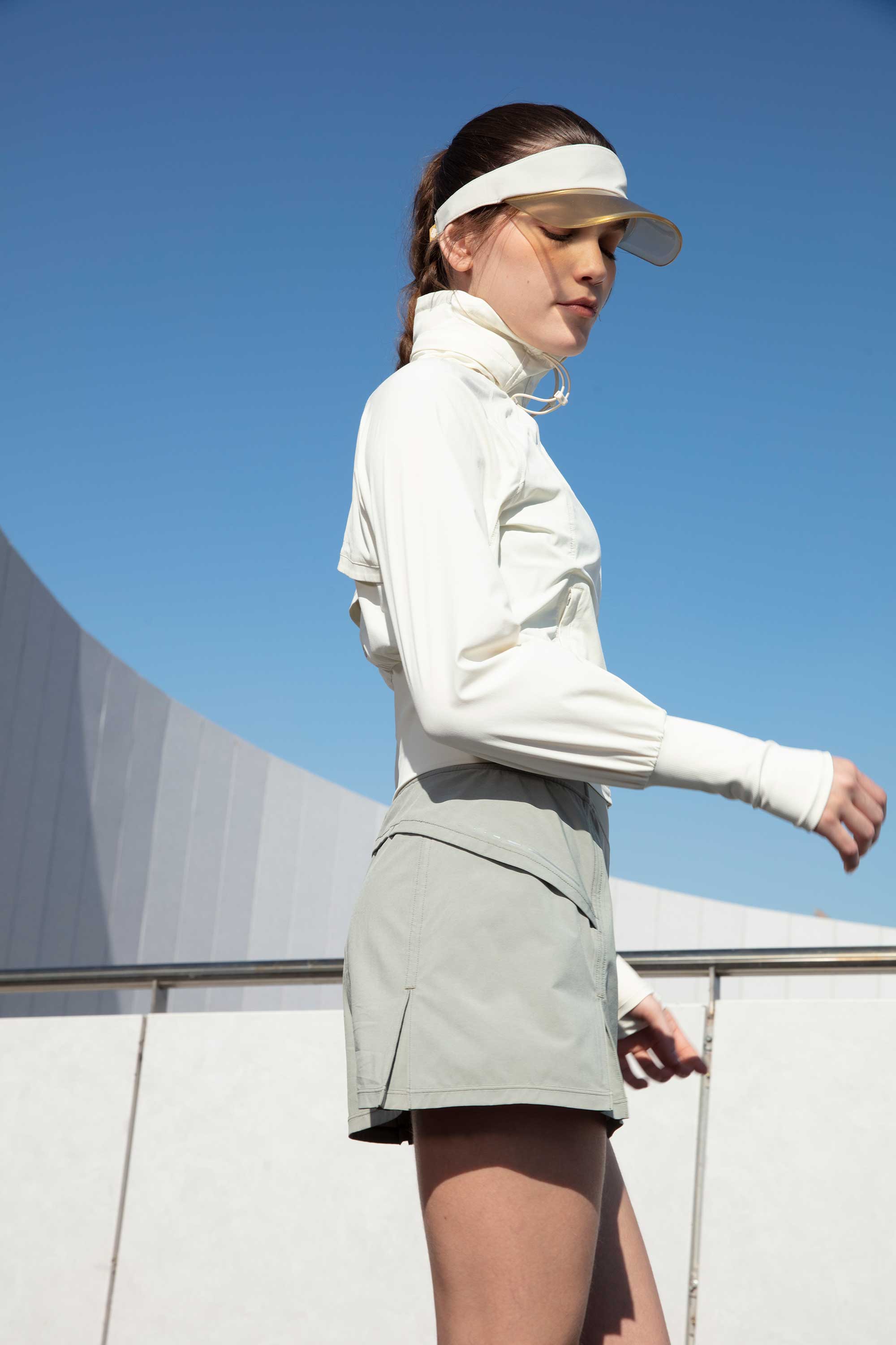 woman in white jacket and grey tennis skort