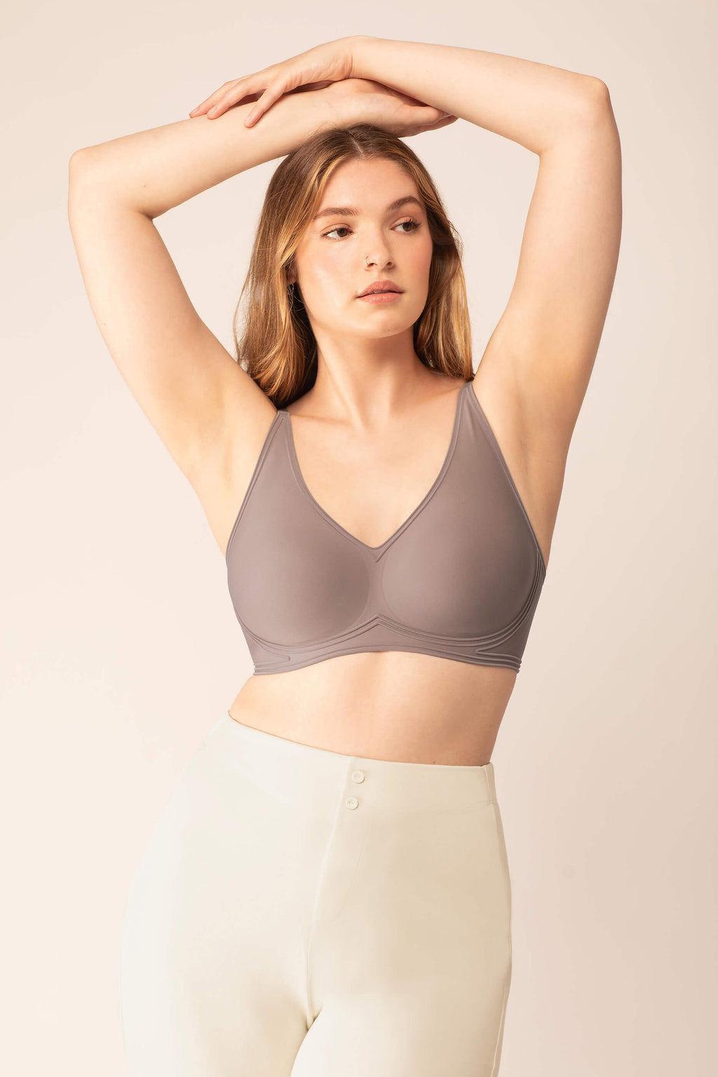 Woman wearing purple grey bra with plunge neckline and white pajama pants