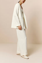 Front side view of model wearing ivory blazer with matching color top and pants.