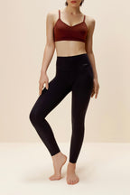 woman standing with dark red bra and black leggings