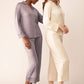 One woman wearing light purple button up pajama shirt with pocket and matching pajama pants next to another woman wearing off-white version of same pajama set