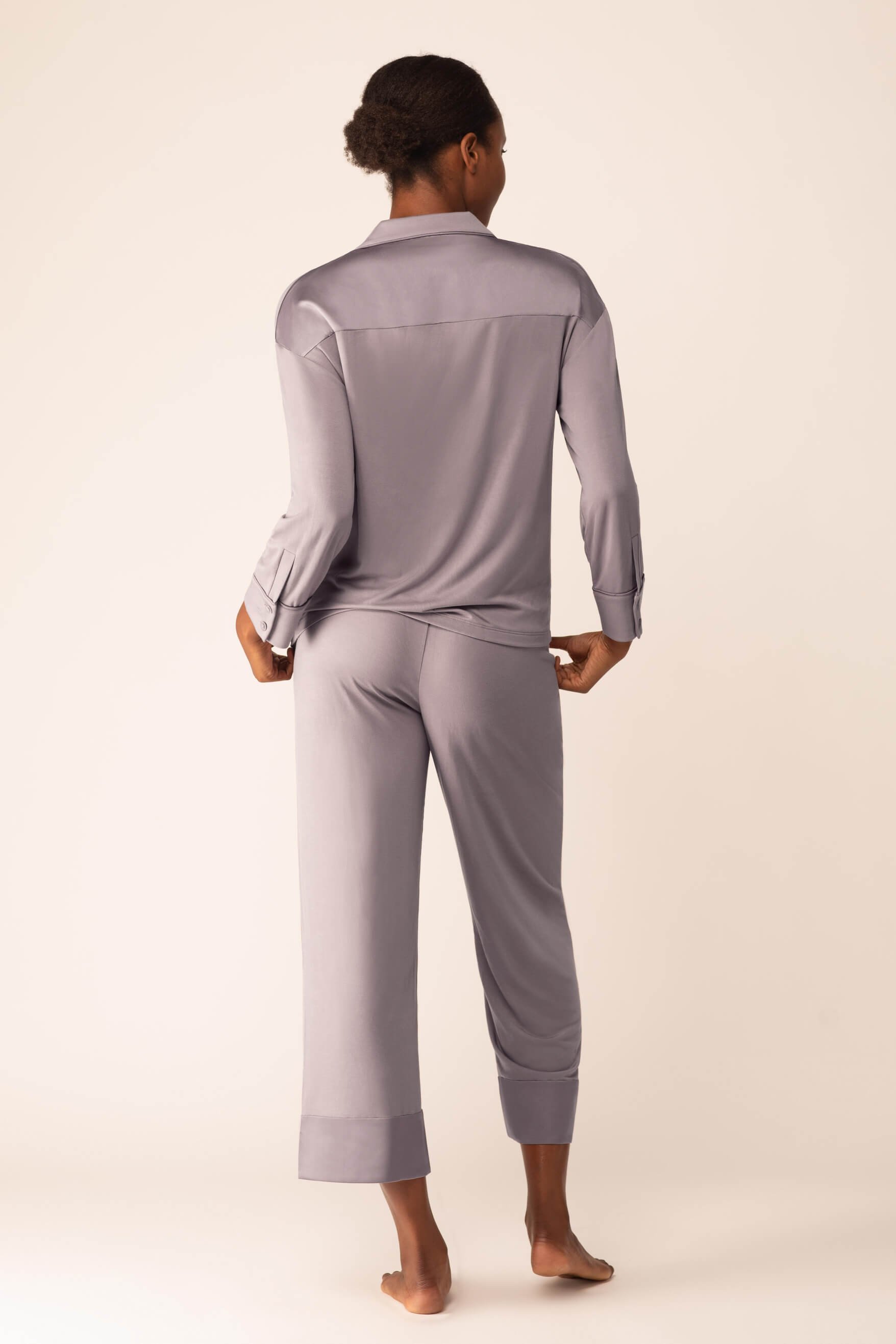 Back view of woman wearing light purple button up pajama shirt and matching pajama bottom