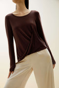 A woman wears a brown sweater and beige pants