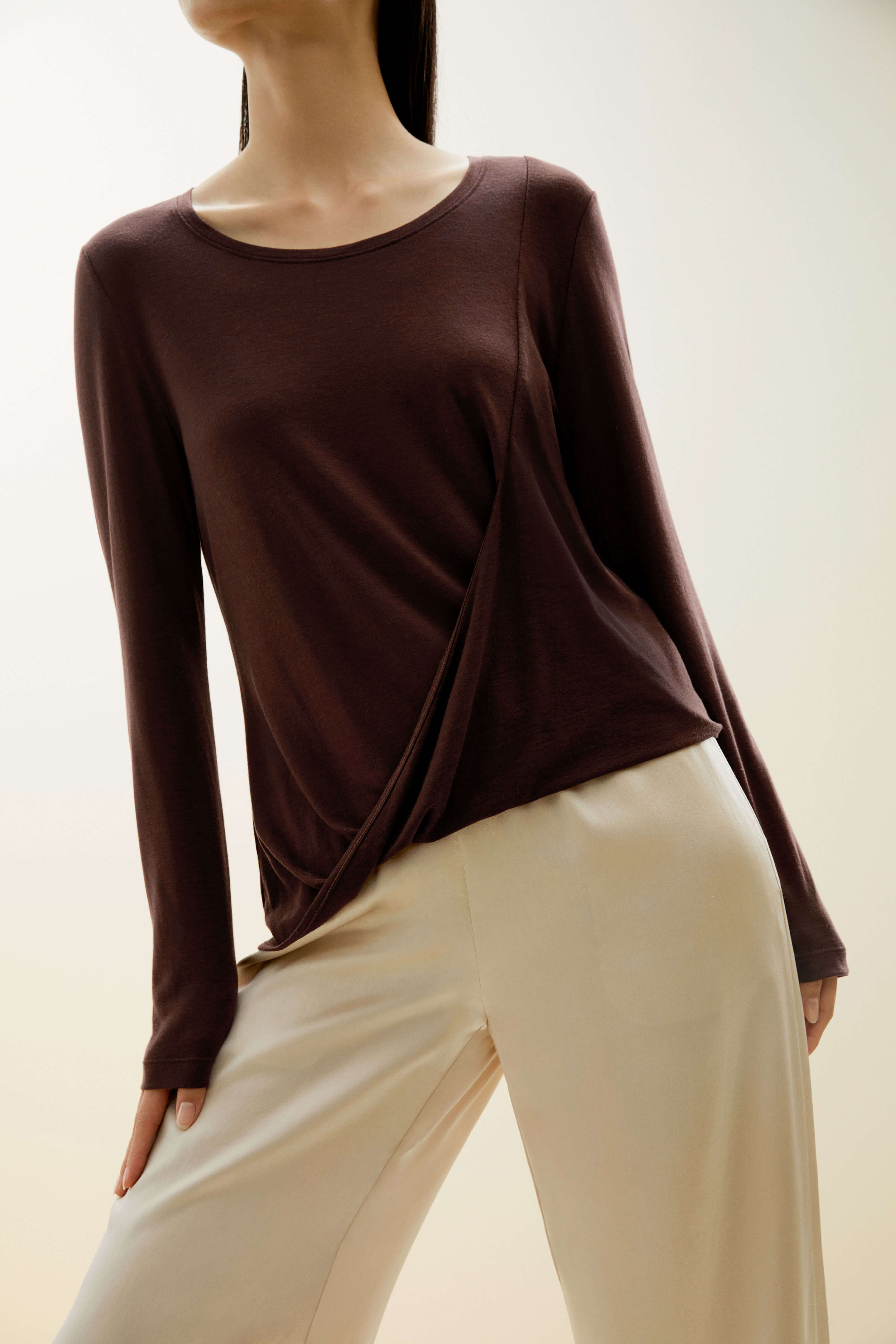 A woman wears a brown sweater and beige pants