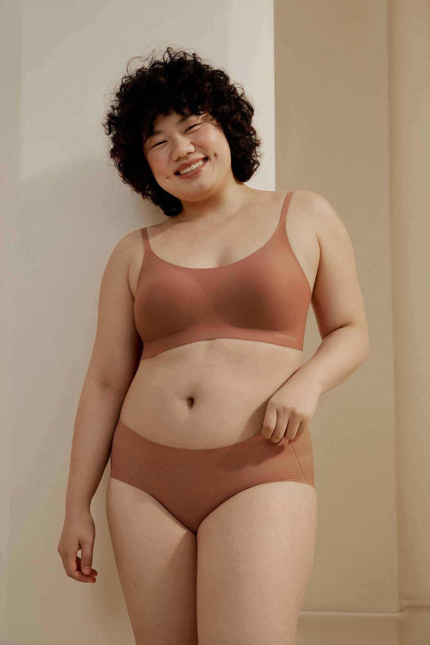 Woman wearing cinnamon color spaghetti strap bra and midwaist seamless brief.