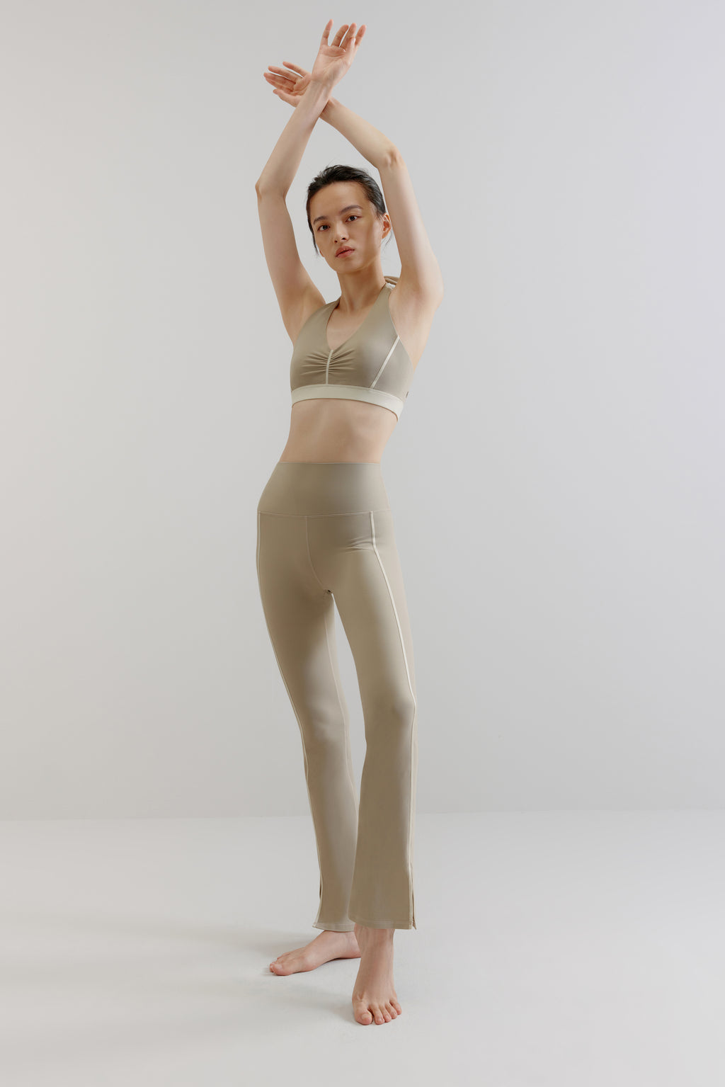 A woman wears a gray sports bra and pants.