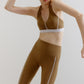 A woman wears an olive green sports bra and leggings