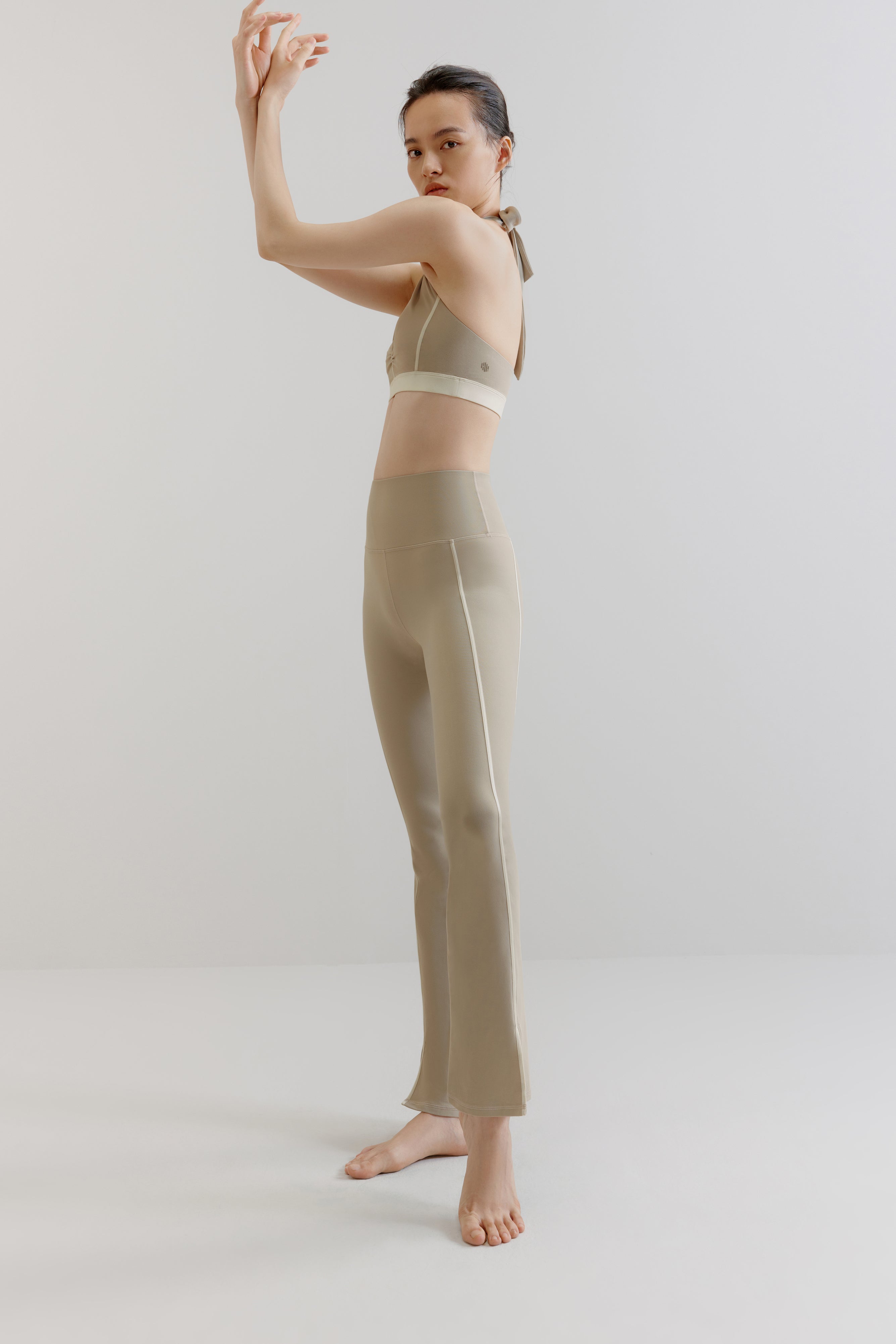 A woman wears a gray sports bra and pants.