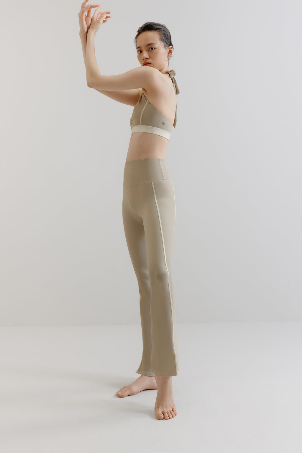 A woman wears a grey sports bra and flare leggings