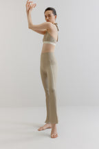 A woman wears a grey sports bra and flare leggings