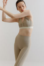 A woman wears a gray sports bra and leggings.