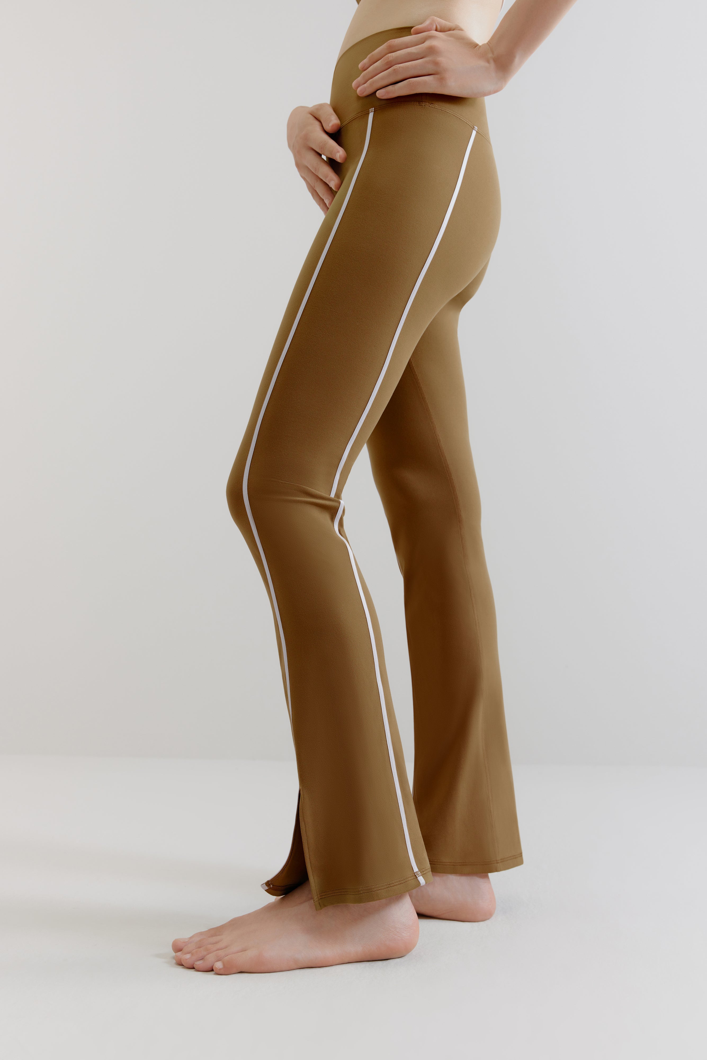 A woman wears olive green flare leggings with two white lines on the sides